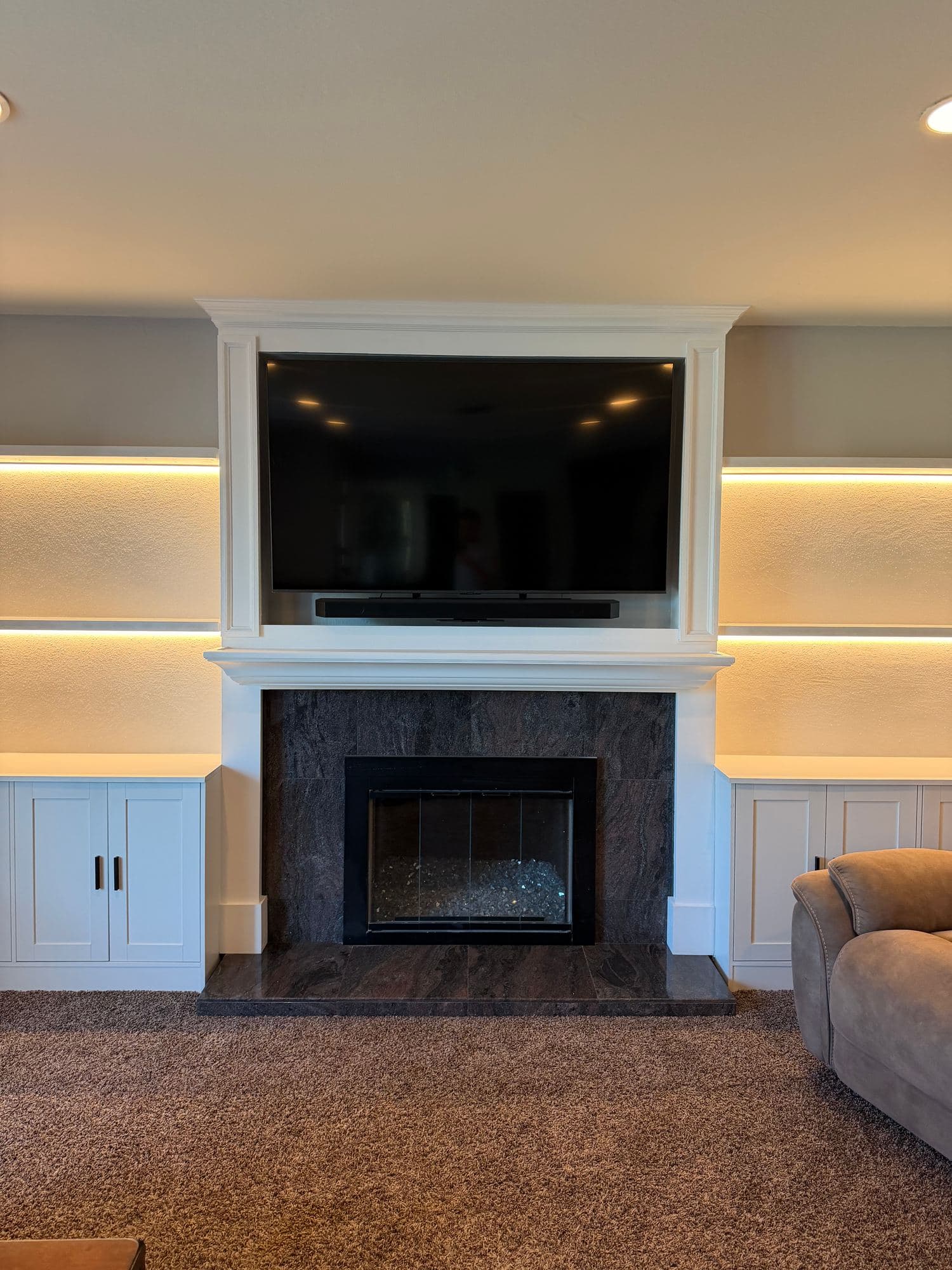 Front view of a white fireplace surround with framed TV niche and LED-lit side shelves
